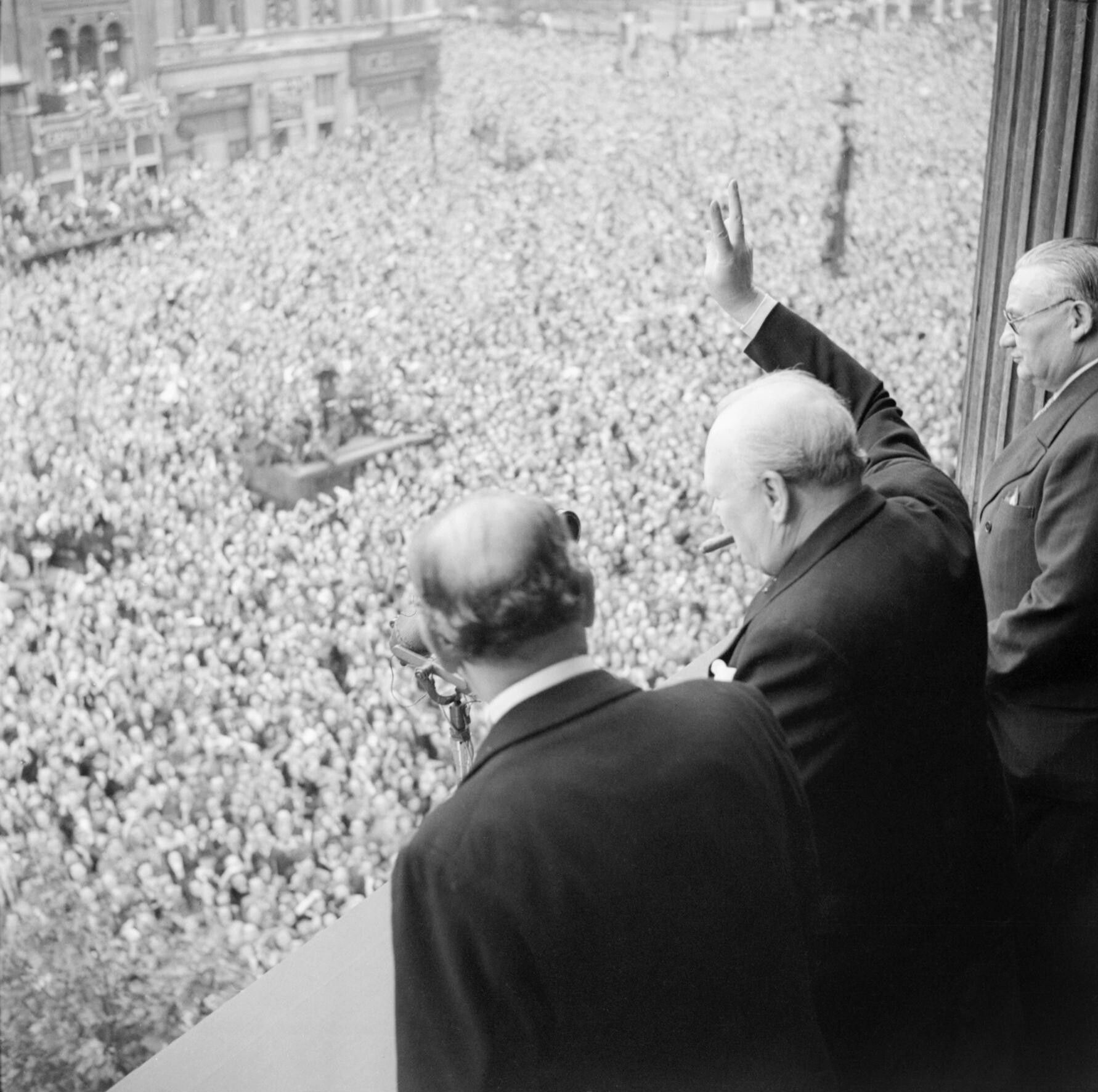 Churchill vinkar till folkmassorna i Whitehall på segerdagen den 8 maj 1945. Fotografi: Imperial War Museum (H 41849), public domain.